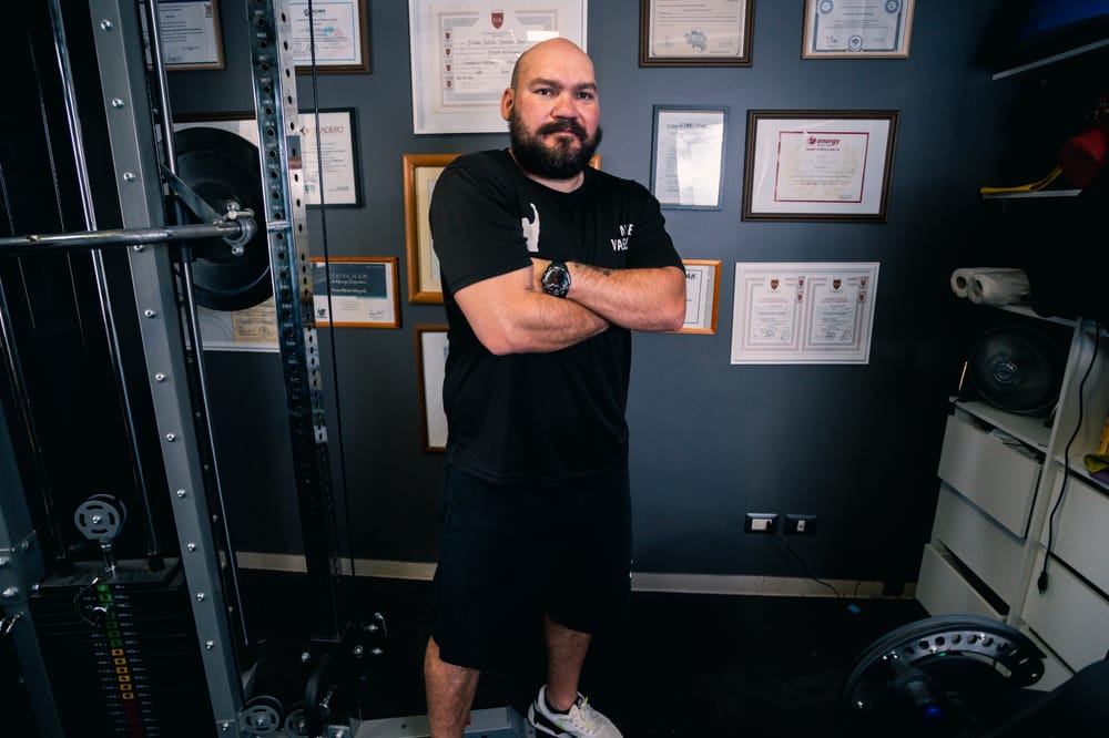 Moisés Valenzuela en el gimnasio, con sus títulos enmarcados detrás
